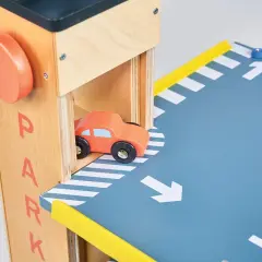 Drewniany parking na autka z pomarańczowym samochodzikiem wjeżdżającym na rampę.