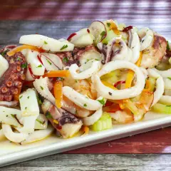 Deliziosa insalata di mare con anelli di calamaro, tentacoli di polpo e gamberi, condita con verdure fresche.