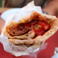 Pyszny, soczysty turecki kebab z mięsem mielonym, pomidorami i ziołami, zawinięty w chrupiące pieczywo.