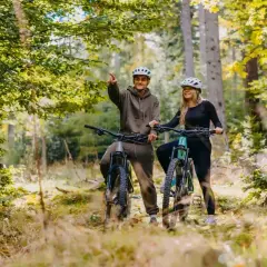 Para odkrywania malowniczych tras rowerowych Szklarska Poręba, para w kaskach na rowerach górskich w lesie.