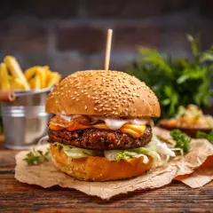 Pyszny burger z bekonem i serem, idealny na dzień burgera. Obok frytki i surówka.