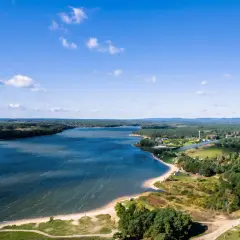 Malownicze jezioro Chańcza otoczone lasami, z piaszczystą plażą i zabudowaniami w tle.