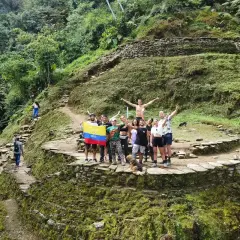 Grupo de turistas celebra en la **ciudad perdida Colombia**, rodeados de ruinas ancestrales y exuberante vegetación.