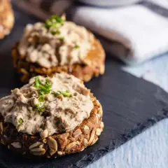 Deliciosos canapés con atún vegano cremoso y cebollino fresco sobre pan integral con semillas.