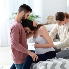 Mężczyzna wspiera ciężarną kobietę, podczas gdy dula oferuje pomoc.