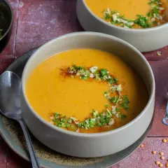 Herzhafte mercimek corbasi, eine cremige Linsensuppe, garniert mit frischen Kräutern und Gewürzen. Daneben eine Schale mit roten Linsen.