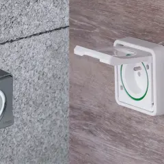 Różne rodzaje gniazdek elektrycznych: szare, natynkowe na betonie i białe, podtynkowe z klapką na drewnie.