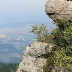 Góry stołowe z dziećmi w oddali, na pierwszym planie skalne formacje porośnięte zielenią.