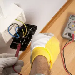 Elektryk sprawdza napięcie w gniazdku. Woltomierz służy do pomiaru napięcia elektrycznego, co jest kluczowe przy pracach instalacyjnych.