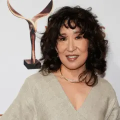 Sandra Oh med en snygg frisyr med halvlångt hår uppklippt i mjuka vågor. Hon bär en beige klänning och ett glittrande halsband.