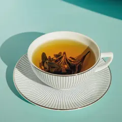 Eine Tasse Kräutertee mit Salbeiblättern, die ihre wohltuende tee wirkung entfalten. Das Geschirr ist weiß mit blauen Streifen.