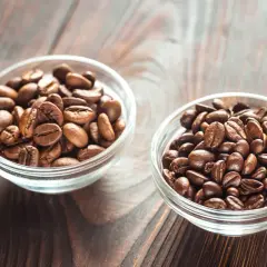 Due ciotole di vetro piene di chicchi di caffè tostati, una con chicchi più chiari, l'altra più scuri, per scegliere tra arabica o robusta.