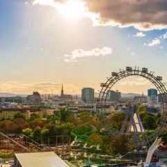 Wiedeń na weekend: panorama miasta z diabelskim młynem i rollercoasterem w Praterze, w słońcu.
