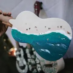 Un ukulélé peint d'une scène de plage animée. La taille ukulele est parfaite pour emporter cette œuvre d'art en voyage.