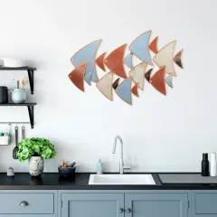 Décoration murale cuisine : un banc de poissons stylisés aux couleurs pastel et terreuses orne le mur blanc au-dessus d'un évier moderne.