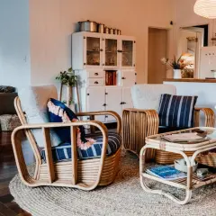 Wnętrze w stylu boho: wiklinowe fotele, stolik, kanapa i biała komoda.