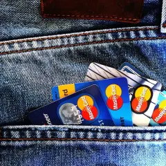 Kilka kart płatniczych, w tym Mastercard, w tylnej kieszeni dżinsów. Czy wiesz, preautoryzacja co to?