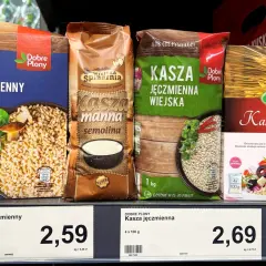 Cztery opakowania kaszy jęczmiennej i kaszy bulgur na półce sklepowej.