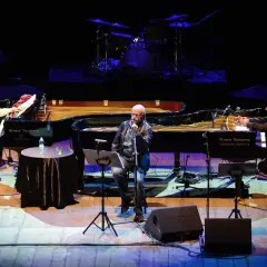 Sergio Cammariere e Enzo Sansone, mano nella mano, suonano i loro pianoforti in un concerto.