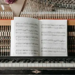 Partition ouverte sur un piano, prête pour un cours de solfège. Les marteaux et les cordes sont visibles derrière la partition.