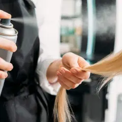 Fryzjerka spryskuje włosy klienta, szukając alternatywy co zamiast lakieru do włosów.