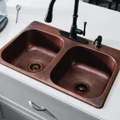 Fregadero doble de cobre martillado con grifo negro. Un truco para limpiar cobre con vinagre es ideal para mantenerlo brillante.