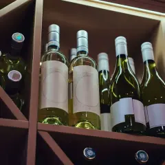Butelki białego wina w drewnianym regale. Idealne miejsce, by dowiedzieć się, jak przechowywać wino, by zachowało swój smak.