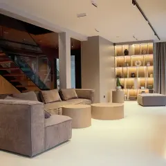 Nowoczesne podłogi wylewane w salonie z wygodną kanapą, schodami i designerską biblioteczką.