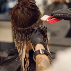 Friseur trägt Farbe auf, um einen sanften Farbverlauf zu erzielen. Die color melting Technik lässt die Töne harmonisch ineinander übergehen.