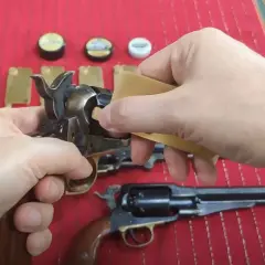Dłonie przygotowują rewolwer do strzału, używając kapiszonów Remington No. 10.