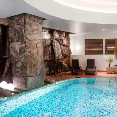 Avslappnande poolområde med stenformationer och bubbelpool, perfekt för en paus efter en dag som viking på ett hotell i Stockholm.