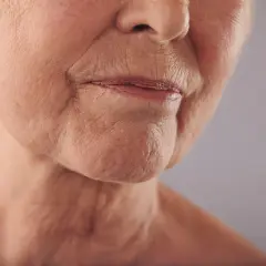 Primo piano del volto di un'anziana, con labbra sottili e rughe della marionetta che raccontano storie di vita.