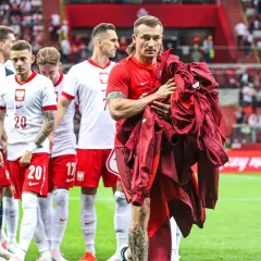 Piłkarze reprezentacji Polski schodzą z boiska. Na pierwszym planie Grzegorz Krychowiak, który trzyma w rękach bordową bluzę. Kim jest Krychowiak? To doświadczony pomocnik, który grał w wielu klubach.