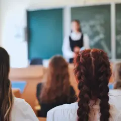 Uczniowie słuchają lekcji o edukacji zdrowotnej. Nauczycielka stoi przed tablicą, a dzieci siedzą w ławkach, skupione na przekazywanej wiedzy.