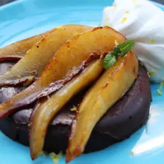 Deliciosa marquesa de chocolate con peras caramelizadas y crema batida, adornada con menta y ralladura de limón.