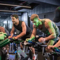 Intensywny trening spinningowy. Grupa ludzi pedałuje na rowerach stacjonarnych, skupiona na wysiłku.