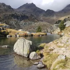 Paisaje sereno en el Vall d'Ora Gorgs, con un lago de aguas cristalinas rodeado de rocas y montañas escarpadas.
