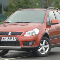 Pomarańczowy Suzuki SX4 z przodu, z widoczną tablicą rejestracyjną.