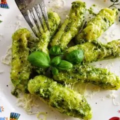 Pyszne gnocchi z zielonym pesto, posypane parmezanem i udekorowane listkami bazylii. Idealne danie na szybki obiad.