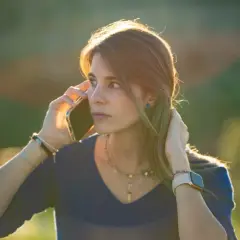 Kobieta z telefonem przy uchu, zaniepokojona, jakby usłyszała, że wybrany numer jest niedostępny.
