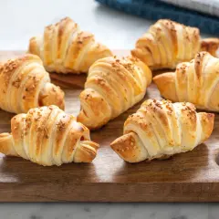 Croissant dorati su tagliere di legno, perfetti per una ricetta pasta sfoglia veloce.