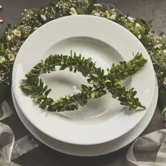 Eleganckie menu na komunię w domu. Na talerzu symbol ryby z gałązek, wokół kwiaty i różaniec.