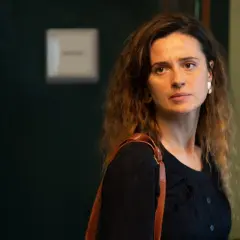 Agnieszka Grochowska, z brązową torbą na ramieniu, patrzy w bok zamyślona.