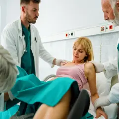 Kobieta w szpitalu, otoczona przez lekarzy, przechodzi przez poród.