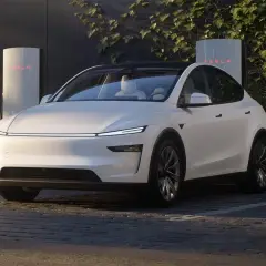 Biała Tesla zaparkowana przy ładowarce Supercharger.