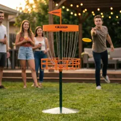 Vänner njuter av en inflyttningsfest med discgolf-lekar i trädgården. En man kastar en gul disc mot korgen.