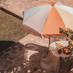 Kolorowy parasol ogrodowy nad stołem z cytrynami i pomarańczami.