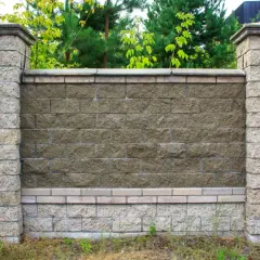 Solidny murek betonowy, obłożony kamieniem, z ozdobnymi słupkami. Idealny pomysł, czym obłożyć murek betonowy, by nadać mu elegancji.