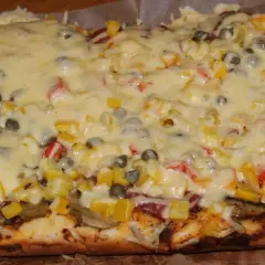 Pyszna pizza na grubym cieście z warzywami i roztopionym serem.