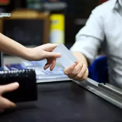 Ręka podaje kartę płatniczą, by zapłacić za zakupy. To prosty sposób na skorzystanie z **cashback co to** jest, czyli zwrot części pieniędzy.